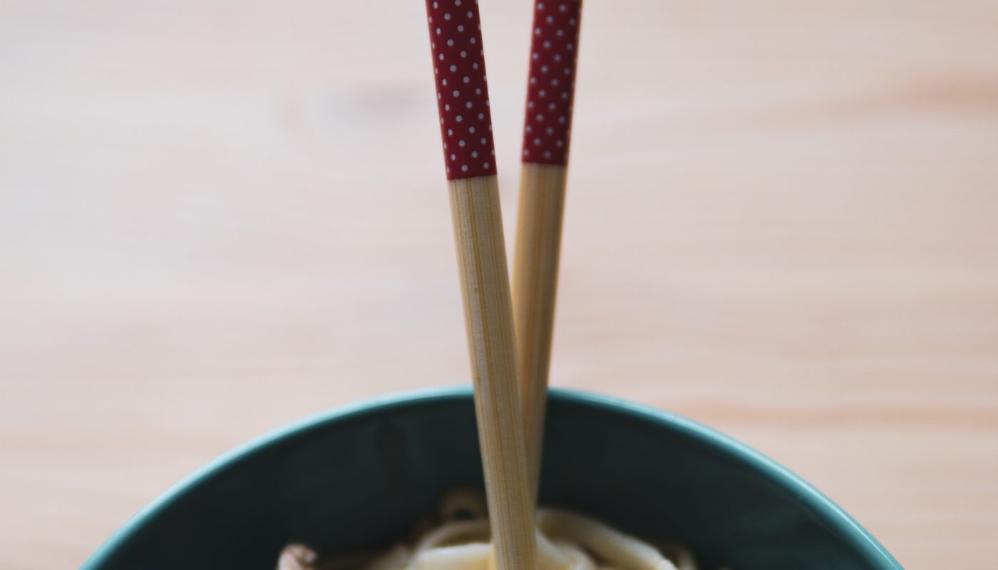 green and white ceramic bowl with brown chopsticks